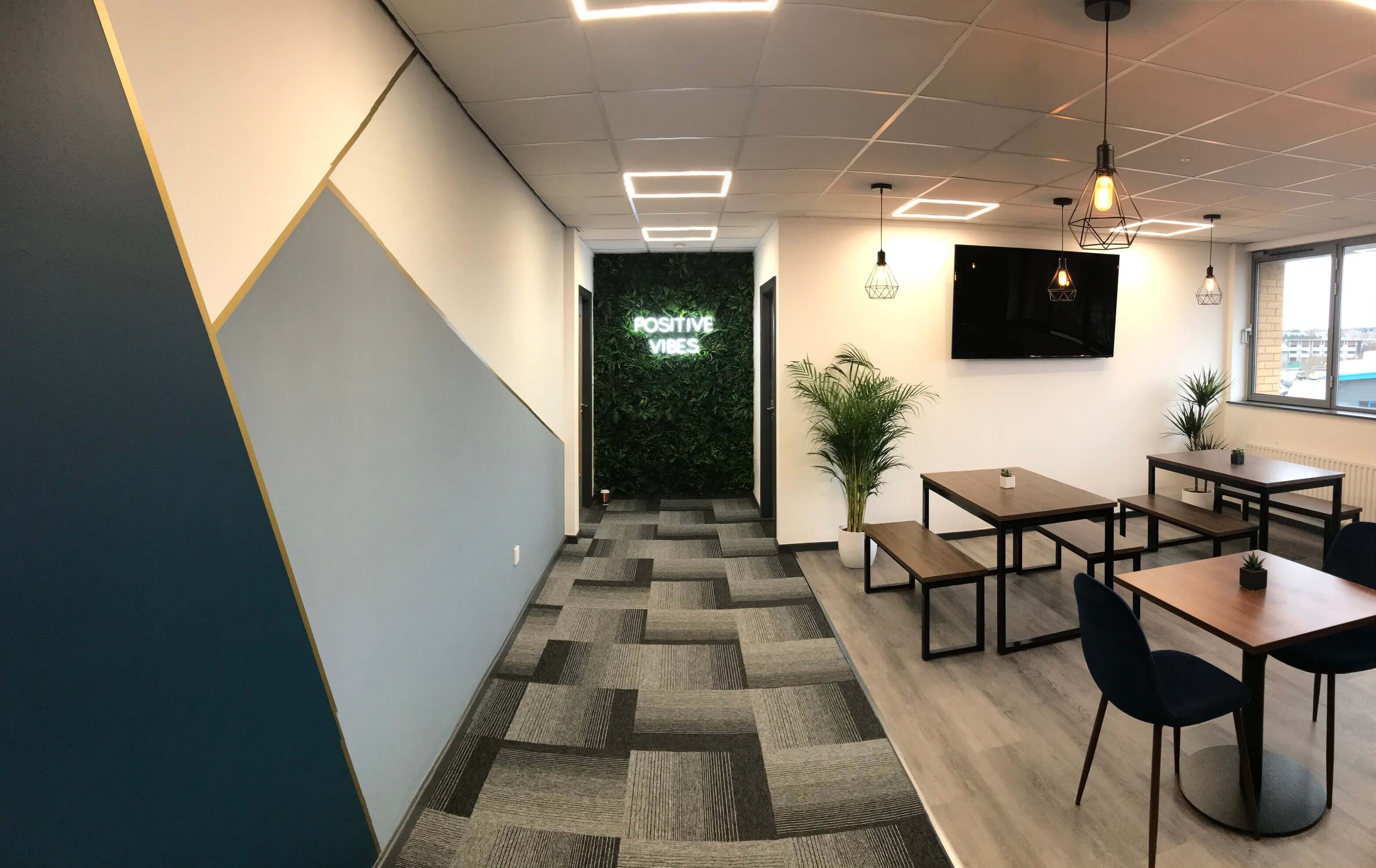 Café seating area with wooden tables and a green plant wall at Hope Park
