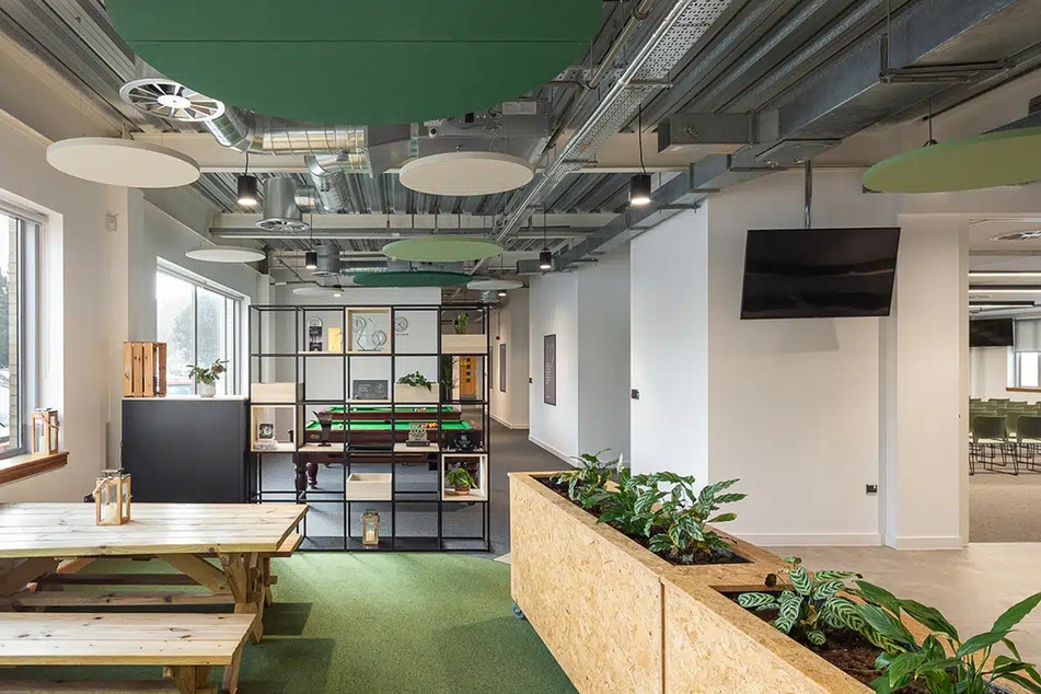 Breakout area with picnic benches, planters and green ceiling panels at Hope Park Jubilee House, Bradford