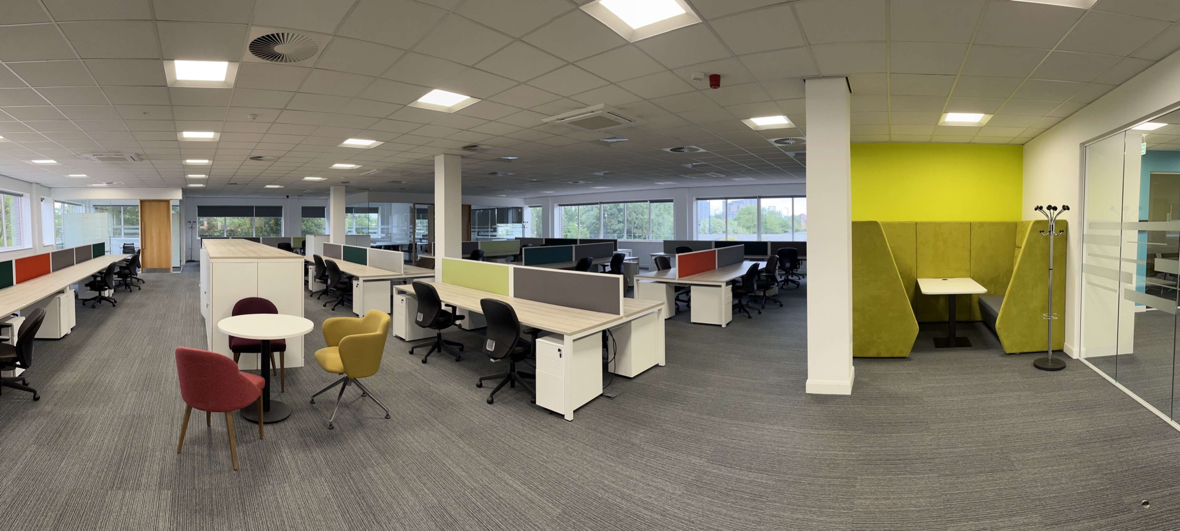 Large open-plan office with desks and a yellow meeting booth at Hope Park Quays Reach, Salford