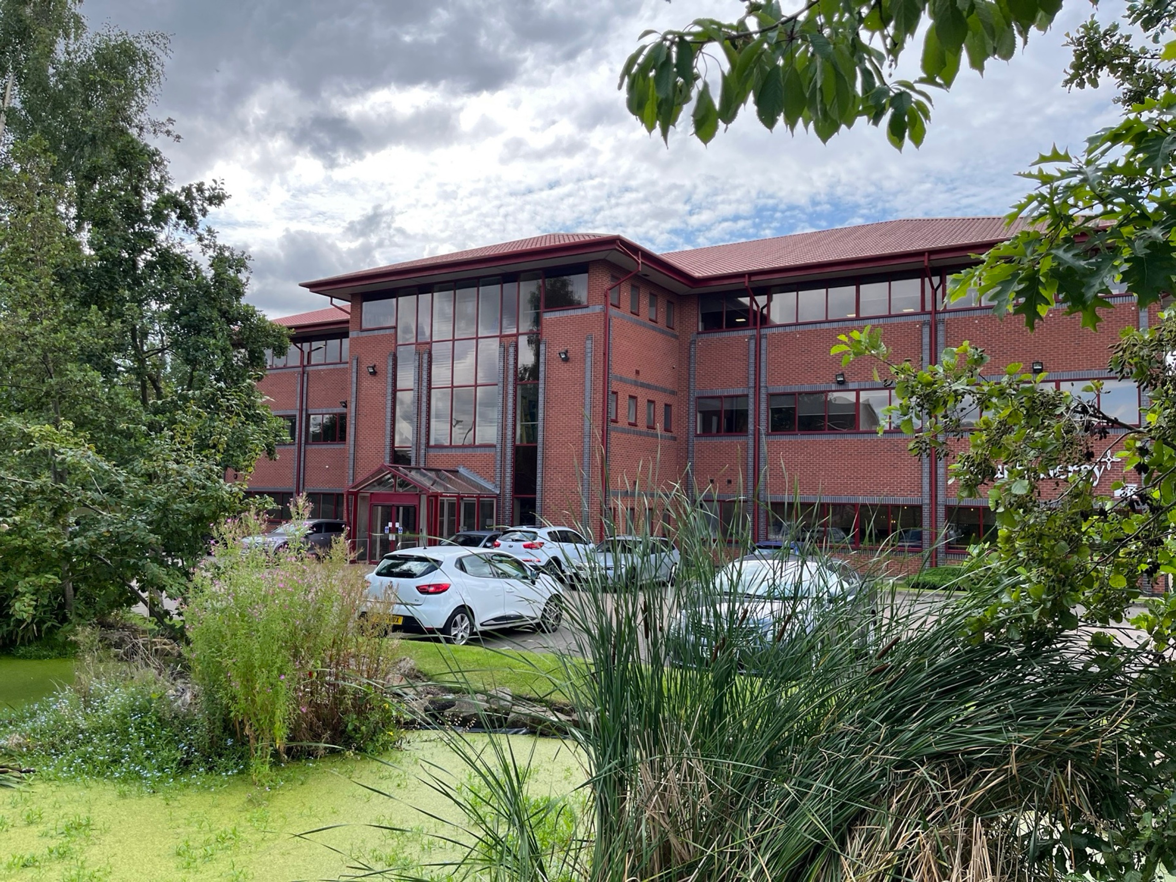 Hope Park Quays Reach, a red-brick office building with a glass atrium entrance, Salford