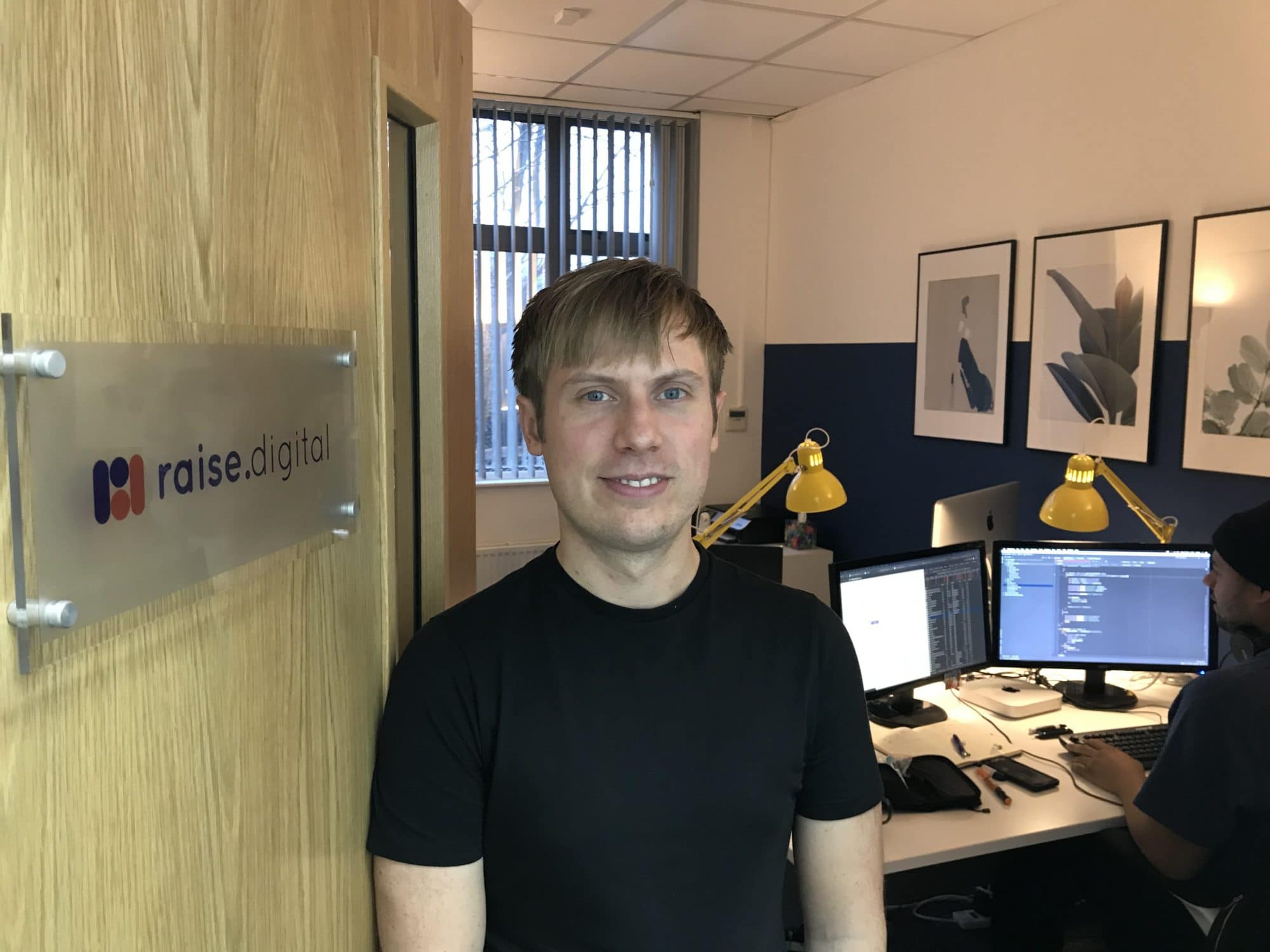 Man posing next to raise.digital signage